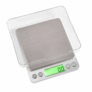 Badger and Dodo Coffee Roasters: Introducing the Envy Series Miniscale 3000g: a sleek kitchen scale with a stainless steel surface, green backlit display at zero, and clear cover. It features three intuitive buttons and handles up to 3000g precisely.