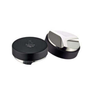 A Motta coffee distribution and leveling tool, made in Italy. The tool has a sleek black and stainless steel design with a flat base and an adjustable leveling blade. One unit is shown with the top view featuring the Motta logo, while the other is flipped to display the angled distribution base.