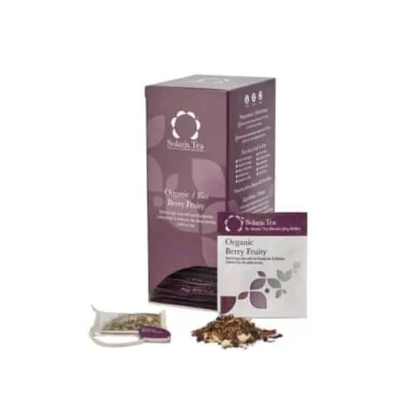 Badger and Dodo Coffee Roasters: A boxed package of Solaris Organic Berry Fruity tea. The vibrant purple box showcases logos and text about the product. In front, an open tea sachet and scattered tea leaves accompany a flat sachet with matching branding, exuding the essence of berry-infused indulgence.