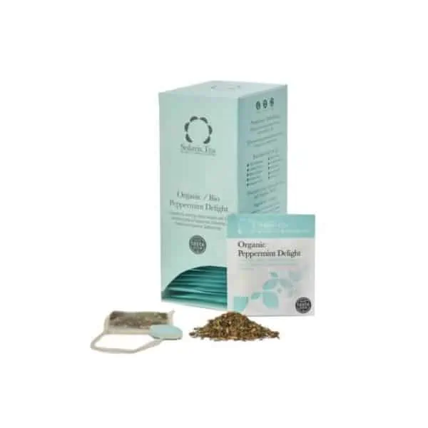 Badger and Dodo Coffee Roasters: A teal box of Solaris Tea labeled Organic Peppermint Delight stands next to a tea sachet and some loose peppermint leaves, exuding an aroma that promises delight. A small packet with matching branding sits invitingly in front of the box.