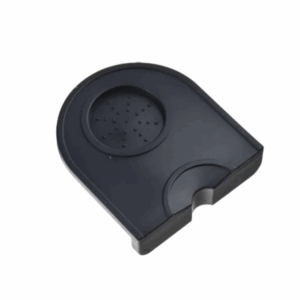 Badger and Dodo Coffee Roasters: The Dropped Edge Tamping Mat is a black plastic, semicircular drip tray with a textured surface, featuring raised dots for grip and a dropped edge for secure positioning.