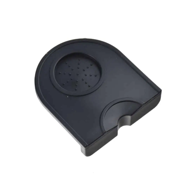 Badger and Dodo Coffee Roasters: The Dropped Edge Tamping Mat is a black plastic, semicircular drip tray with a textured surface, featuring raised dots for grip and a dropped edge for secure positioning.